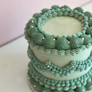 two-tier sage green cake with vintage shell piping and white pearls