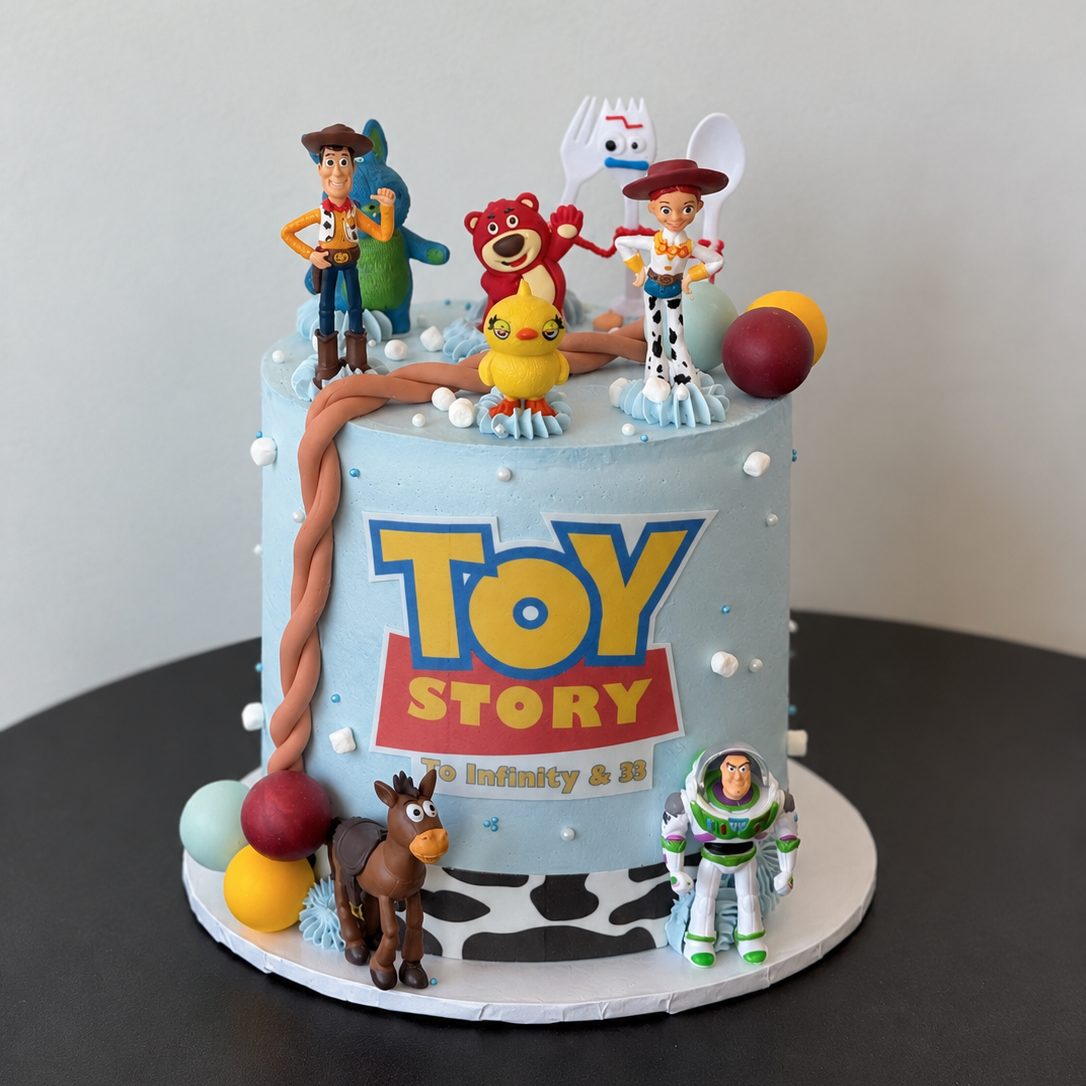 light blue cake with toy figures on top, a printed title plaque and colourful spheres