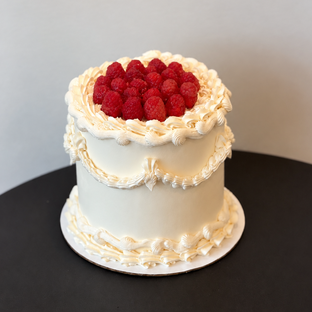 ivory vintage-piped cake topped with fresh raspberries