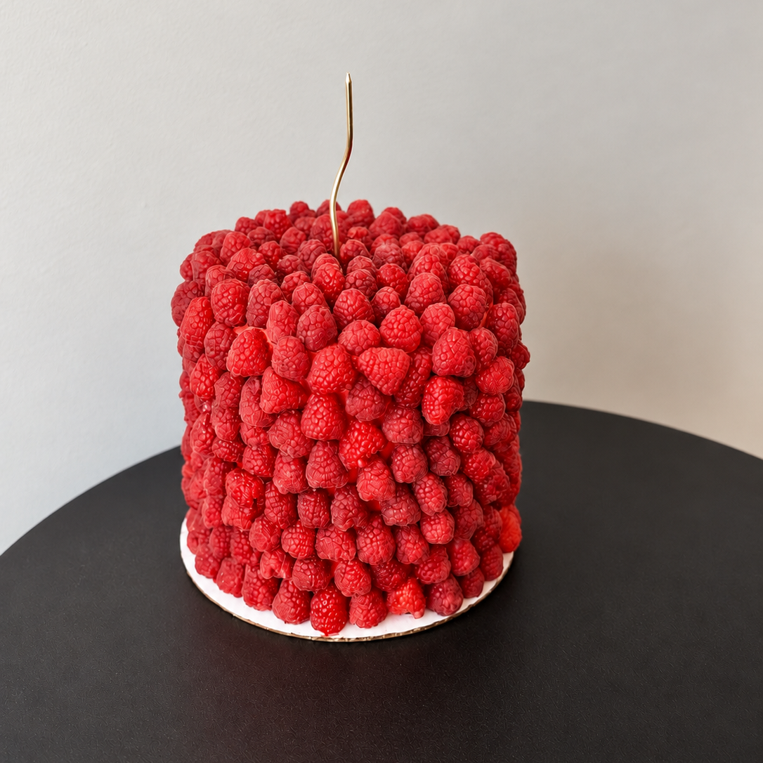 round cake covered in fresh raspberries with a gold stem decoration